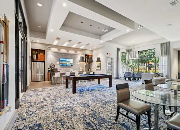 A living room with a blue carpet and a glass table.