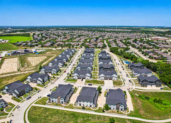 A large suburban housing development with rows of houses and a clear sky.