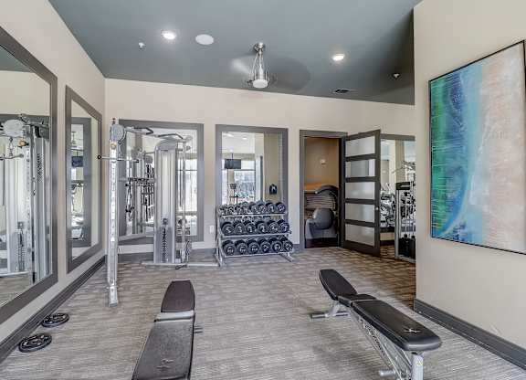a fitness room with cardio machines and a large painting on the wall