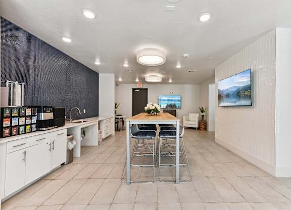 A modern kitchen with a dining table and chairs in the center.