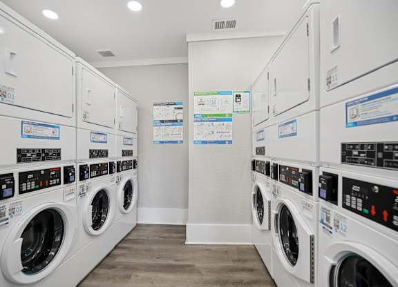 A row of white front load washing machines in a laundromat.