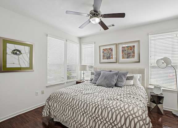A bedroom with a patterned bedspread and a ceiling fan.