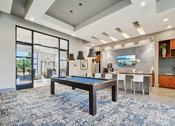 A pool table is in the middle of a room with a blue carpet.