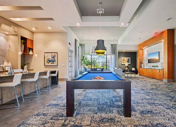 A billiard table is in the middle of a room with a blue rug.