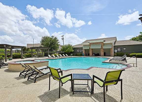 A pool with chairs around it and a building in the background.
