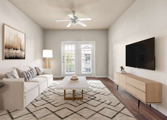 Bright living room with white sofa, wall-mounted TV, and French doors to balcony.