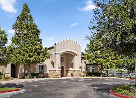 The Bradford community building exterior with arched entryway, stone accents, and mature trees.