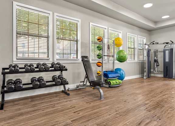 Fitness center with free weights, workout bench, and functional training equipment.