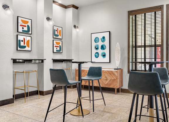 Social nook with bar-height tables, modern stools, and framed artwork accents.