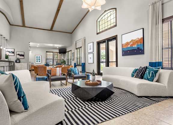 Spacious resident clubhouse with high ceilings, lounge seating, and kitchen bar area.