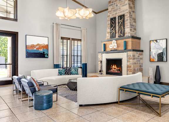 Clubhouse lounge at The Bradford featuring stone fireplace, modern sofas, and pendant lighting.