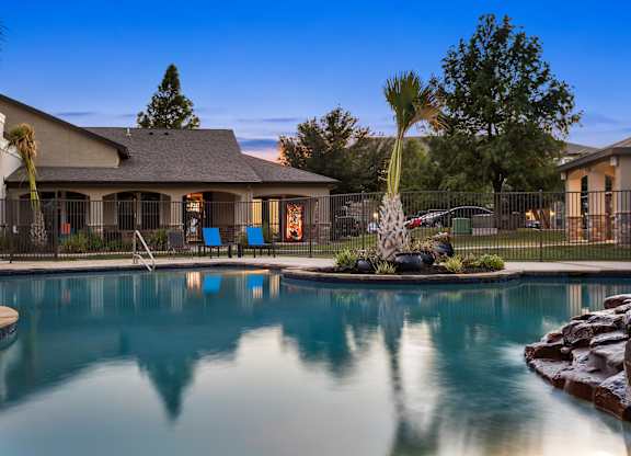 Resort-style pool at The Bradford in Buda, TX with twilight reflections and palms.