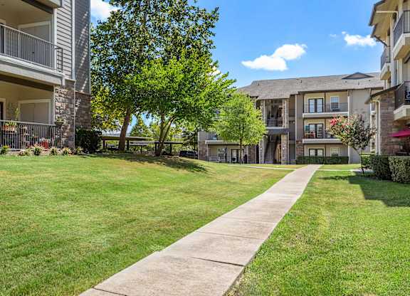 Landscaped walkway at The Bradford with sidewalk, green lawn, and apartment buildings.