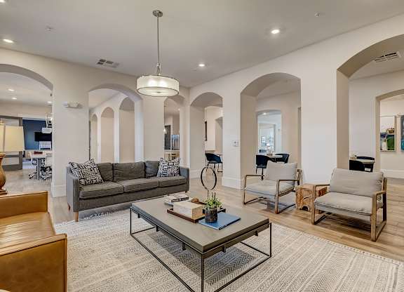 A modern living room with a grey couch, a glass coffee table, and a wooden chair.