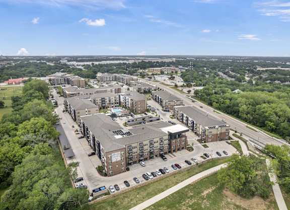an aerial view of an apartment complex with trees and a highway