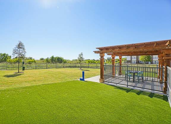 A sunny day at a park with a wooden structure and a fence.