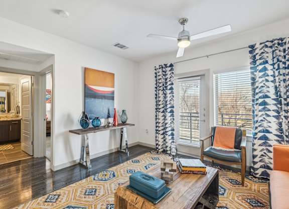 A living room with a rug, a chair, a table, and a painting on the wall.