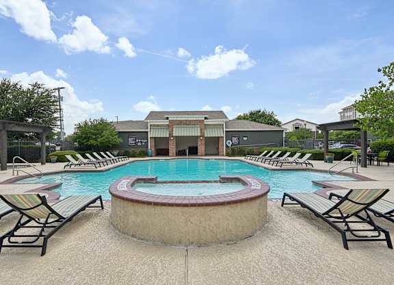 A pool with lounge chairs around it.