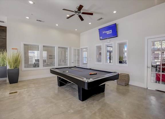 Indoor game room with pool table, wall-mounted TV, and polished concrete floors.