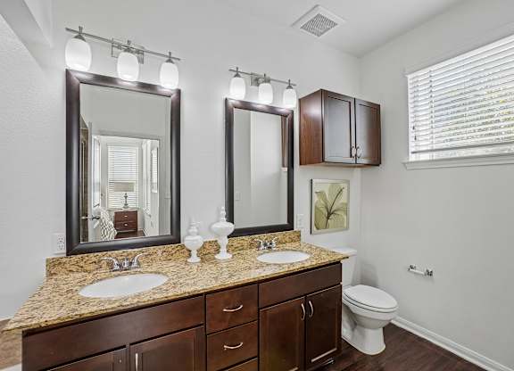 A bathroom with a granite countertop and a large mirror above it.