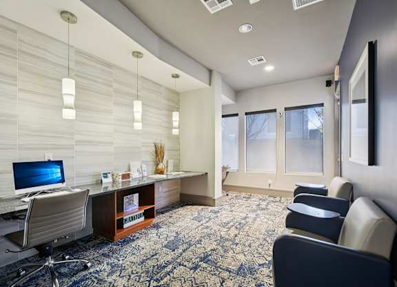A room with a desk, chairs, and a patterned carpet.