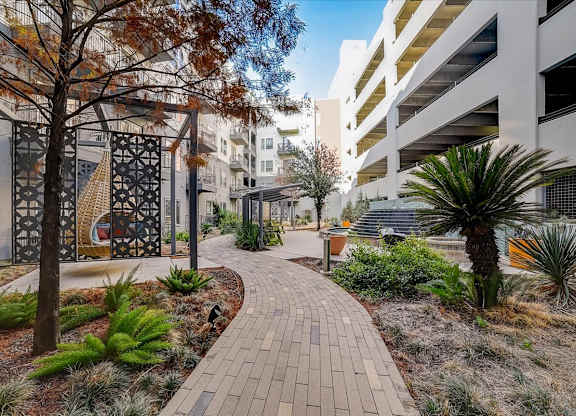 A walkway with a tree and plants on either side.