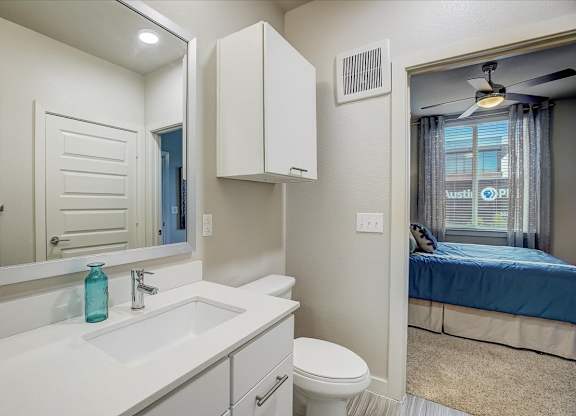 Bathroom vanity with large mirror and bright sink, beside hallway toward the bedroom.