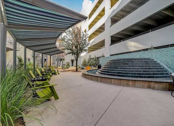 A patio with a row of chairs and a pool in the background.