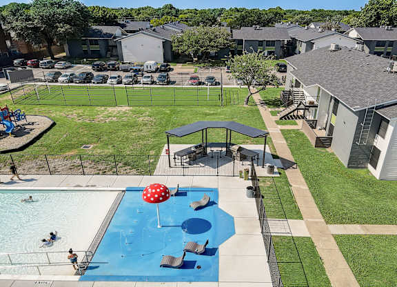 an aerial view of a backyard with a pool and volleyball court
