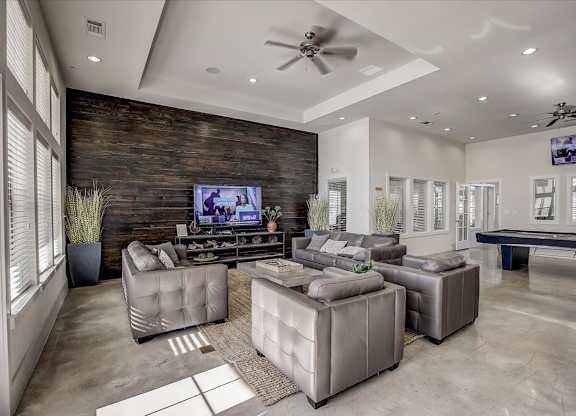 Clubhouse lounge with leather seating, large TV, and game room area.