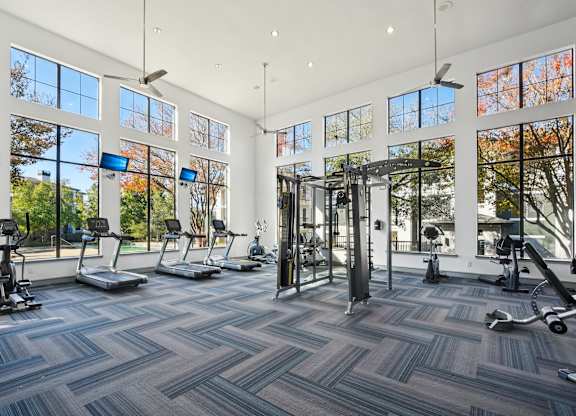A spacious gym with a variety of equipment and large windows.