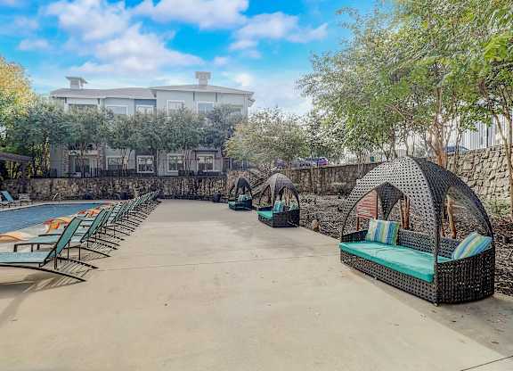a resort style swimming pool with lounge chairs and a hotel in the background