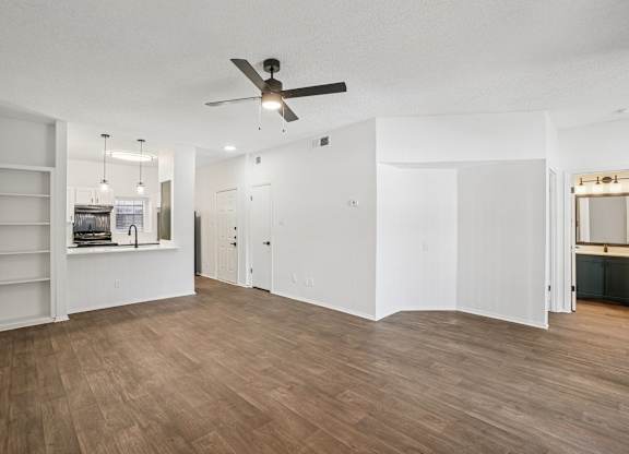 A room with a ceiling fan and wooden flooring.