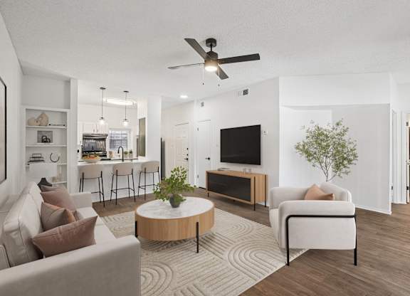A living room with a white couch, a wooden coffee table, and a ceiling fan.