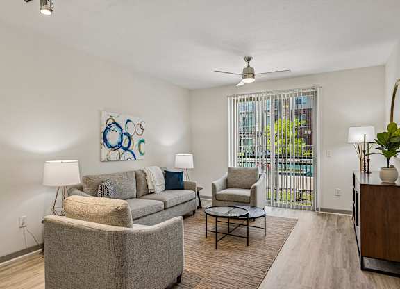A living room with a grey couch, a chair, a table, and a painting on the wall.