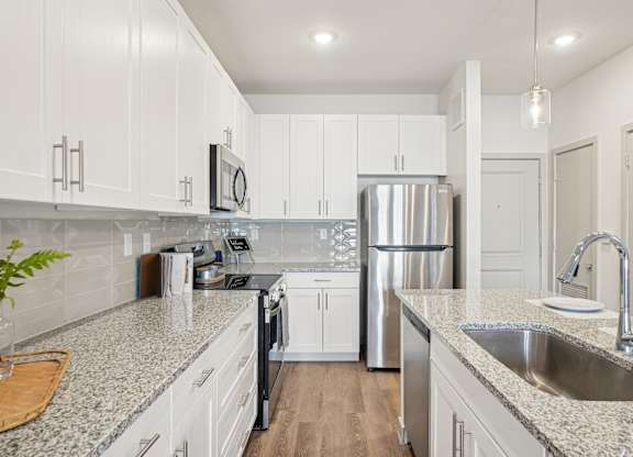 A kitchen with white cabinets and a granite countertop.