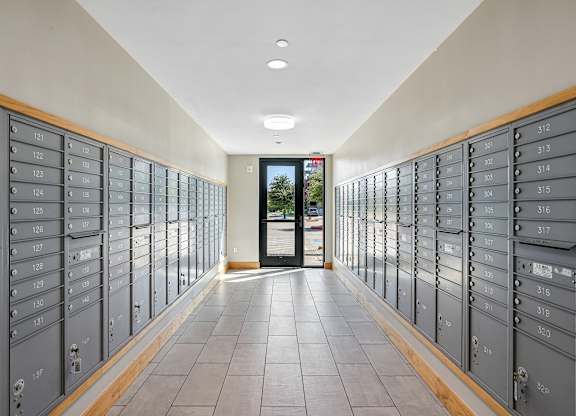 A long hallway with mailboxes on both sides and a door at the end.