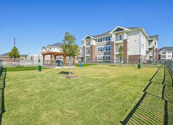 A large grassy area in front of a multi-story apartment building.