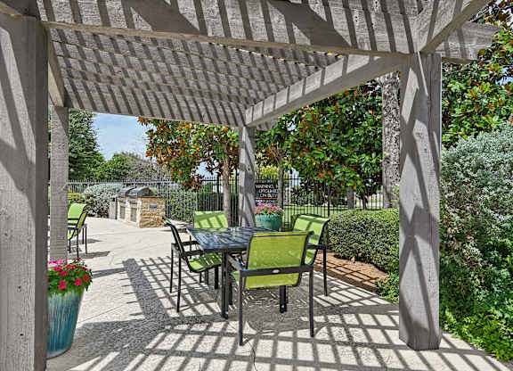 A patio with a table and chairs under a pergola.