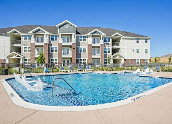A large swimming pool in front of a multi-story apartment building.
