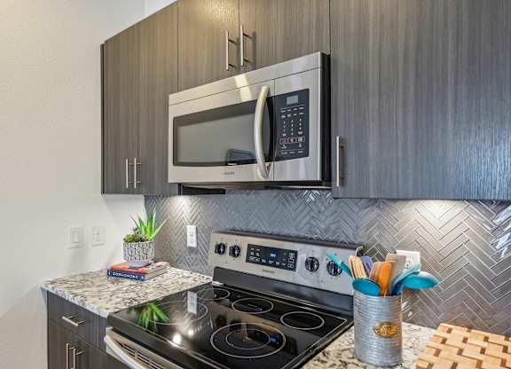 A modern kitchen with a stainless steel oven and microwave above it.