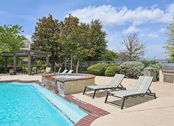 A pool with a red brick border and striped lounge chairs.