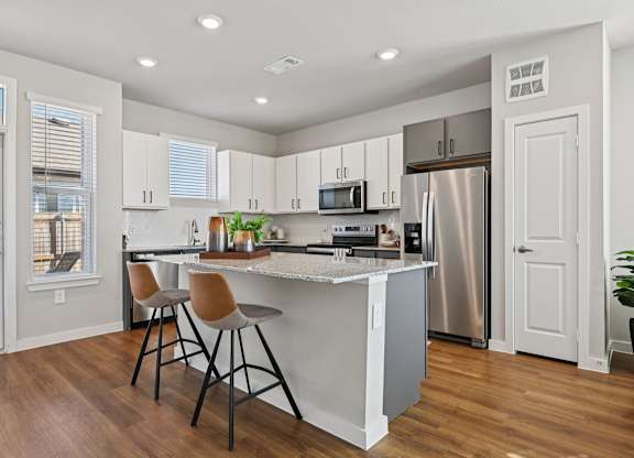 A kitchen with white cabinets and a wooden floor.