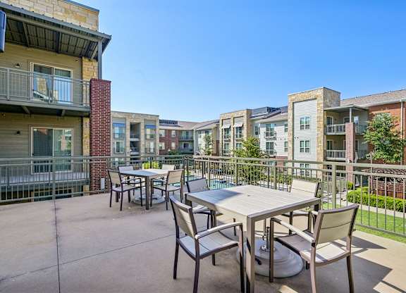 A patio with a table and chairs is surrounded by apartment buildings.