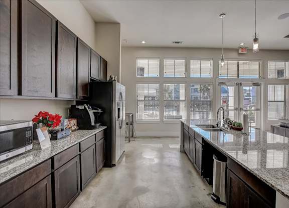 Clubhouse kitchen with long granite island, pendant lights, and window wall.