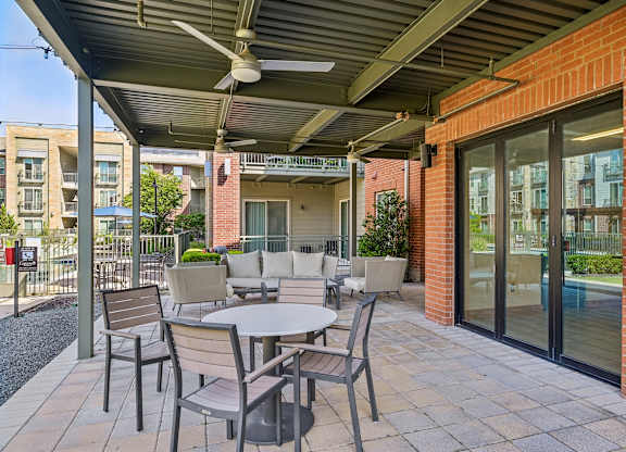 A patio with a table and chairs under a roof.