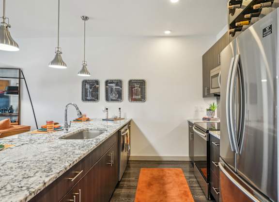 A modern kitchen with a marble countertop and stainless steel appliances.
