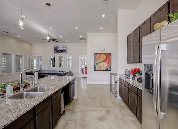 Clubhouse kitchen and game room with granite island and stainless refrigerator.
