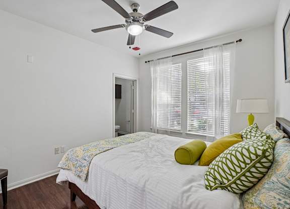 A bedroom with a bed, pillows, and a ceiling fan.