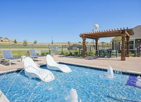 A pool with a waterfall and a pergola.